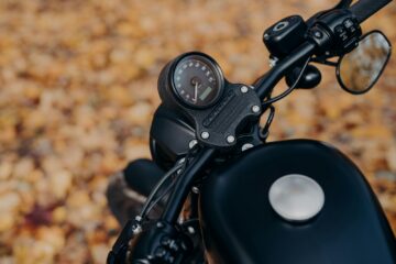 Black motorbike against ground covered with orange foliage in autumn park