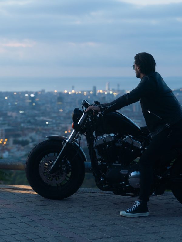 Biker or moto rider after sunset, doing his trip ride with beautiful city views at background