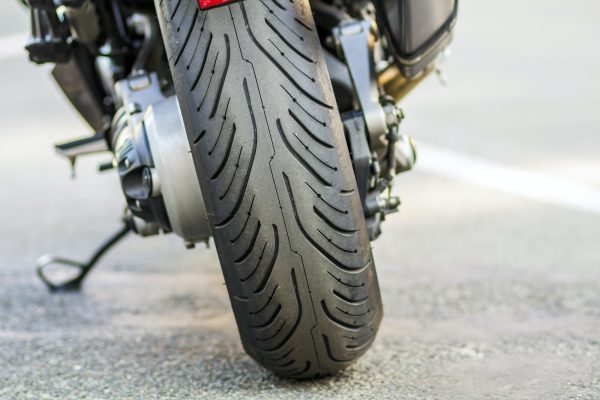 Rear wheel of sports motorcycle on road. Motorbike parked on a street. Freedom and travel concept.